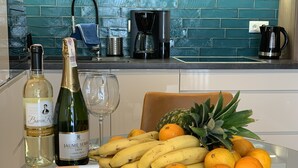 A kitchen counter with a bottle of wine, a glass, and a plate of fruit. - ApartmentSun Parrot (Wroclaw)