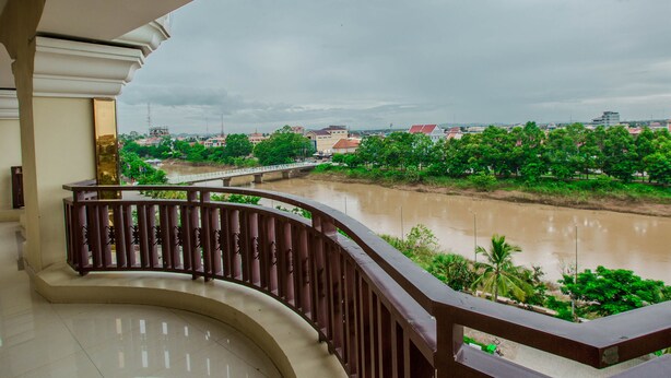 A balcony with a view of a river, greenery, and distant buildings. - VY CHHE Hotel (Battambang)