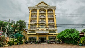 A multi-story hotel with a yellow facade, balconies, and a sign indicating it is a hotel. - VY CHHE Hotel (Battambang)