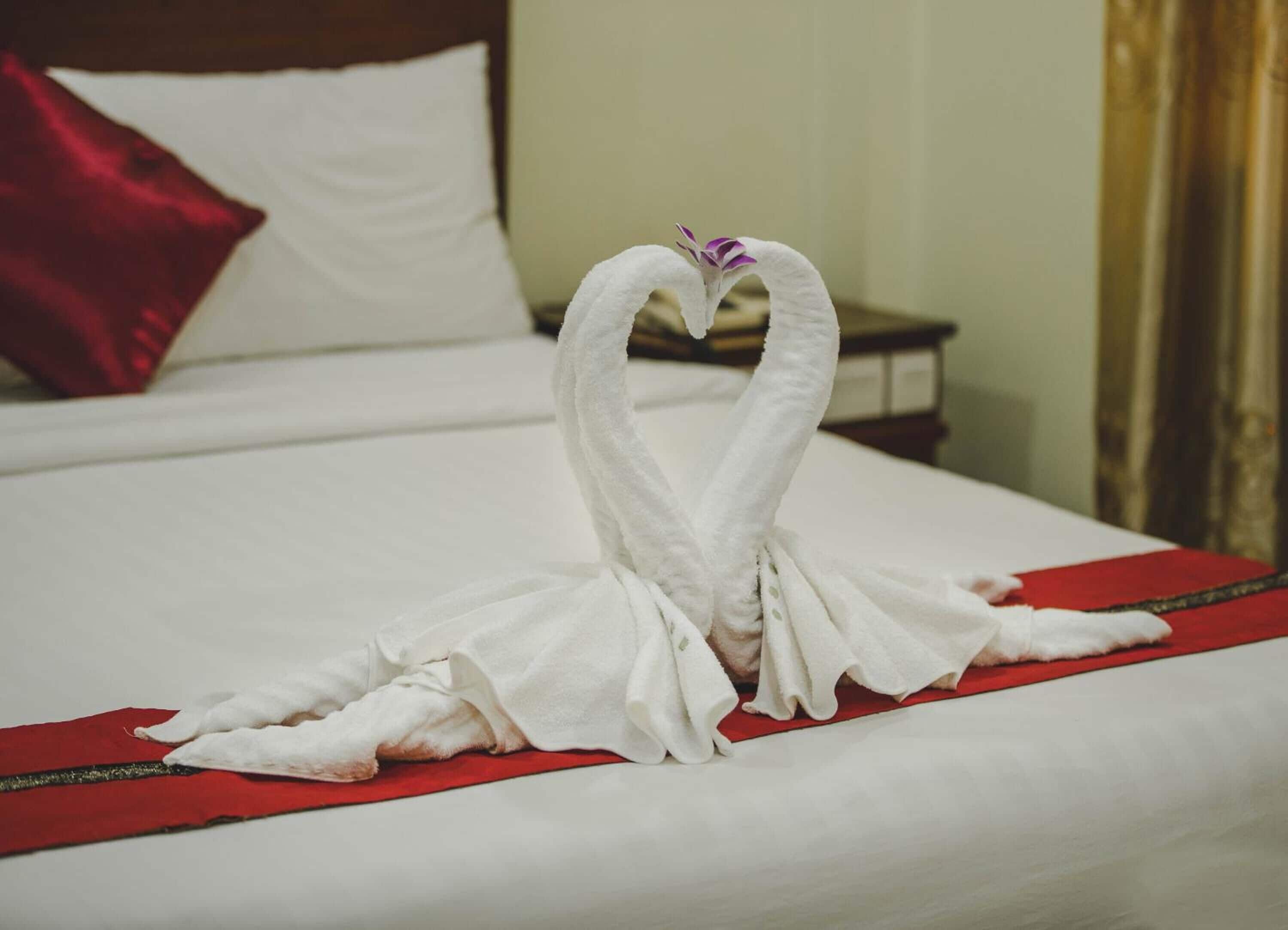 A bed with a red bedspread and a white pillow.