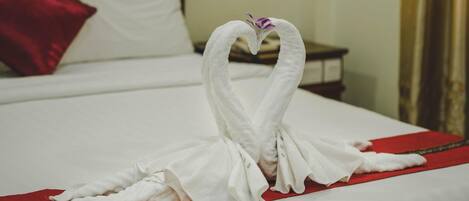 A bed with a red bedspread and a white pillow.