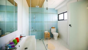 Een badkamer met een douchecabine van glas, een toilet en een bad.