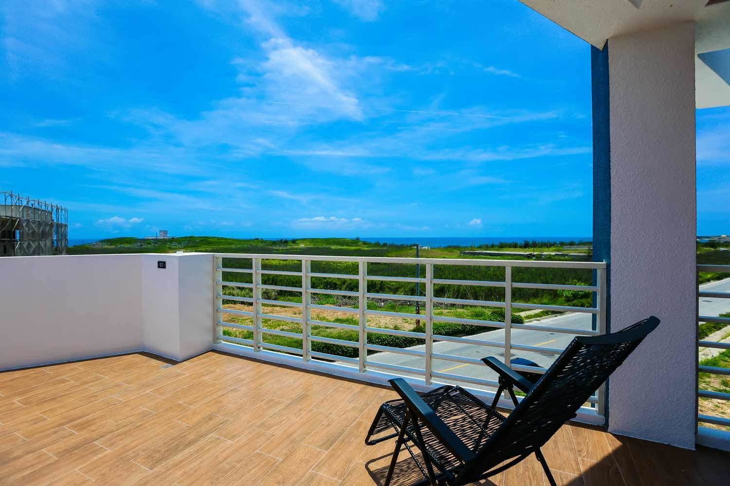 A balcony with a view of a green landscape and a road.