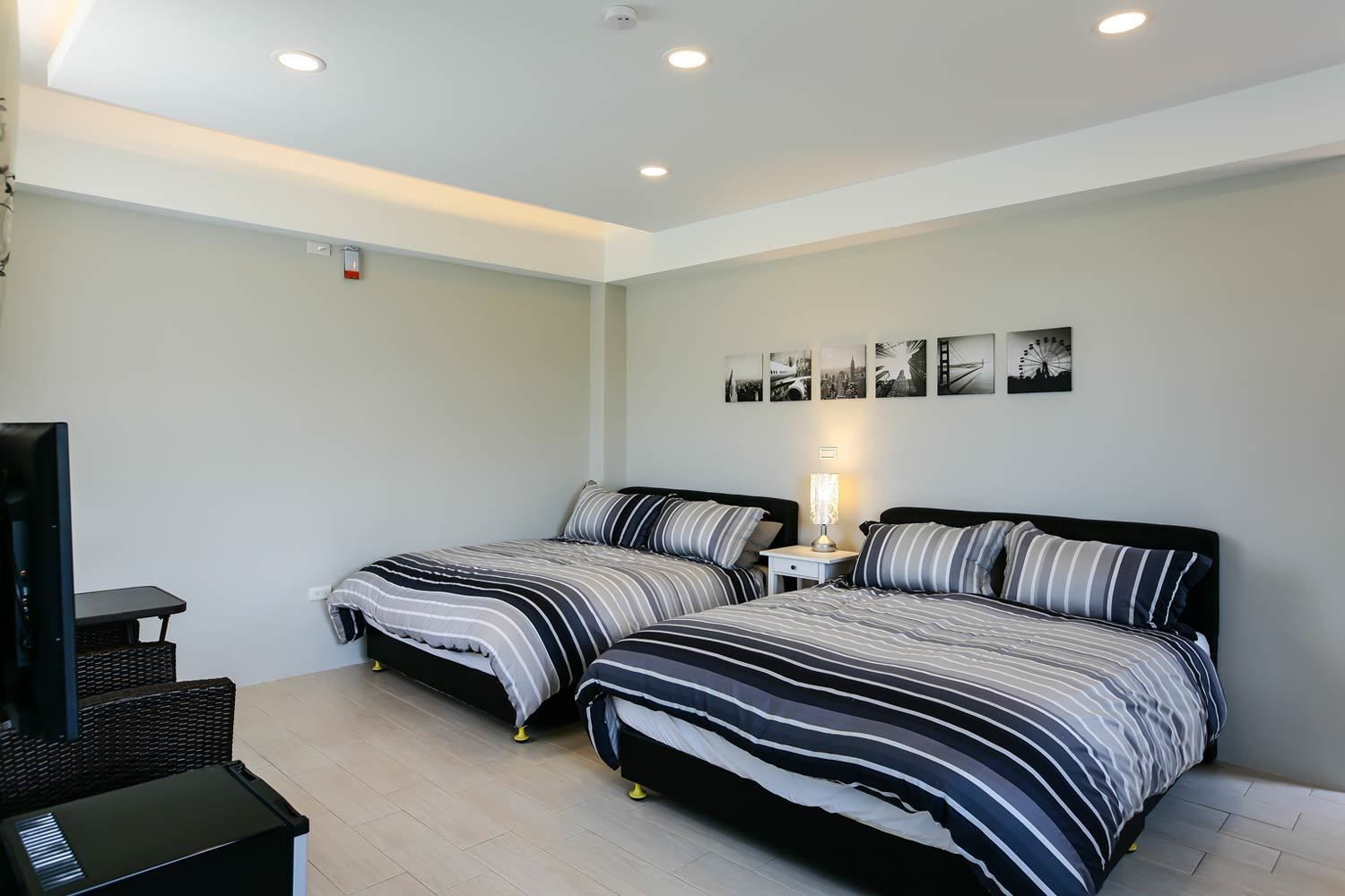 A modern hotel room with two beds, a desk, and a TV.