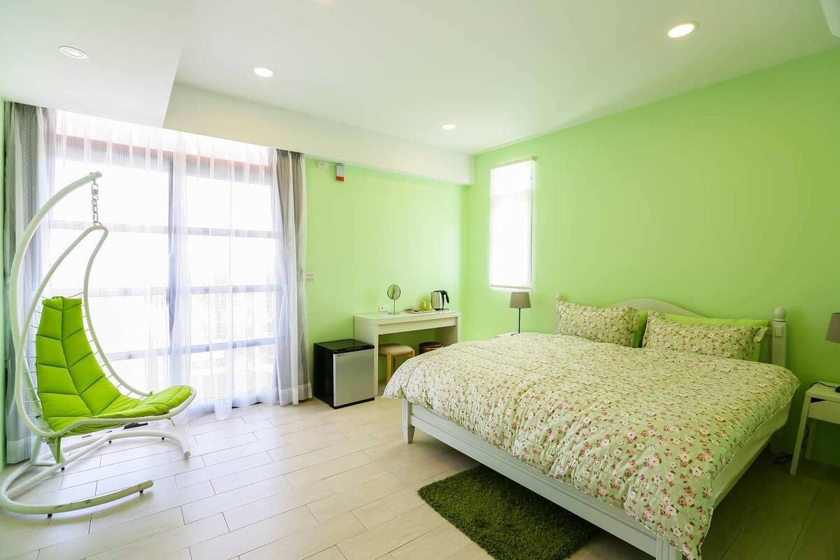 A bedroom with a bed, a desk, a chair, and a small heater.