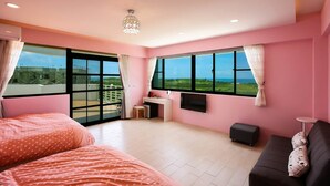 Een slaapkamer in roze kleurstelling met twee bedden, een bureau en een bank.
