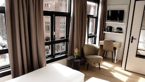 A hotel room with two beds, a desk, a chair, a TV, and a window with curtains. - Hotel van Gelder (Amsterdam)