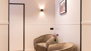 A modern interior with two beige armchairs, a wall-mounted light fixture, and a framed picture. - Hotel van Gelder (Amsterdam)