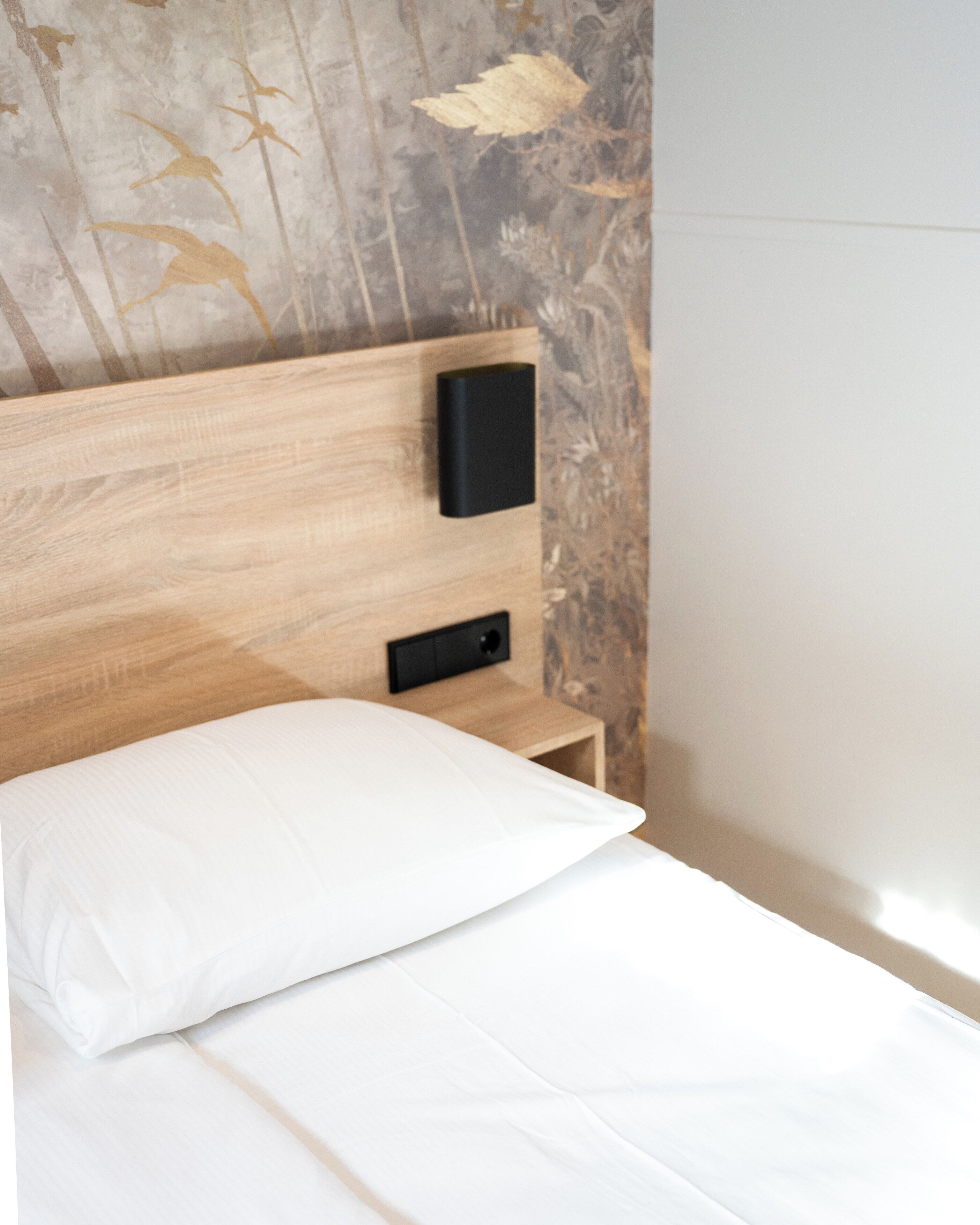 A bed with a white pillow and a wooden headboard.