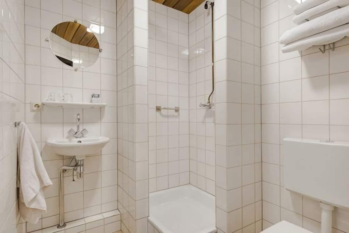 A bathroom with a sink, mirror, shower, and towel rack.