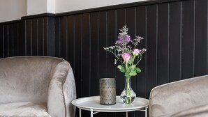 A room with two grey armchairs, a small white table with a patterned candle holder, and a vase with flowers. - Hotel van Gelder (Amsterdam)