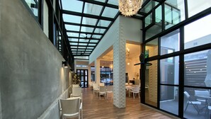 A spacious indoor area with a high ceiling, large windows, and wooden flooring. - Good News Homestay (Hengchun)