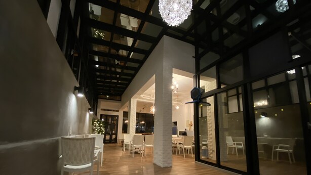 An interior with a wooden floor, white chairs, a chandelier, and large windows. - Good News Homestay (Hengchun)