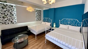 A modern bedroom with two single beds, a sofa, a small table, and a decorative wall. - Good News Homestay (Hengchun)