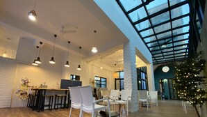 A spacious indoor area with a high ceiling, wooden flooring, and white furniture. - Good News Homestay (Hengchun)