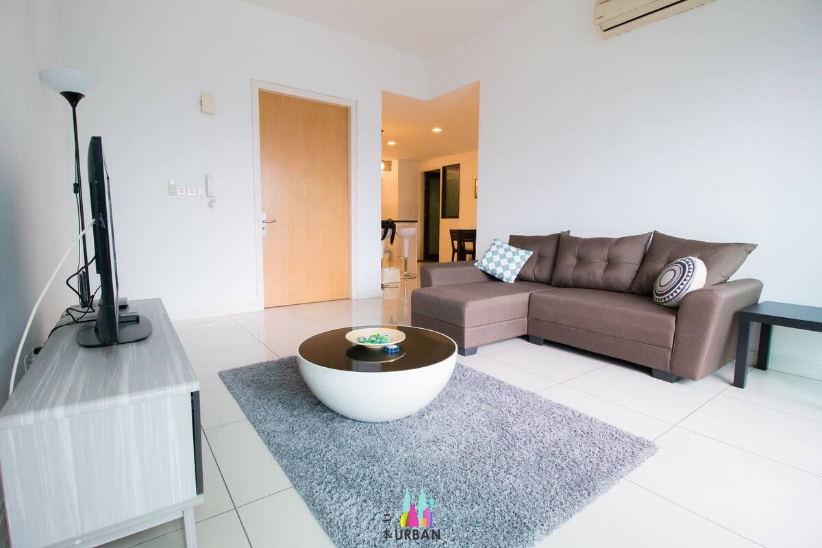 A modern living room with a sofa, a coffee table, a TV, and a lamp.