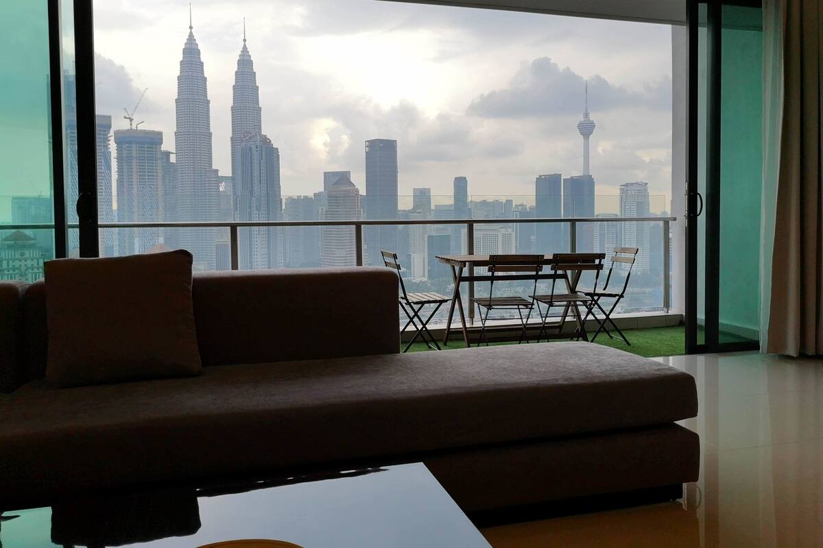 A modern living room with a large window overlooking a city skyline, including prominent skyscrapers.