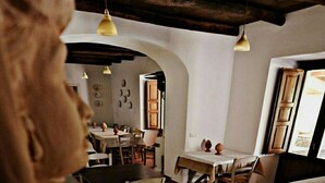 Ein Interieur mit Holzbalken, Tischen, Stühlen und Pendelleuchten.