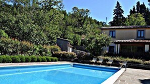 Ein rechteckiger Pool mit einer Steindeck und Liegestühlen.