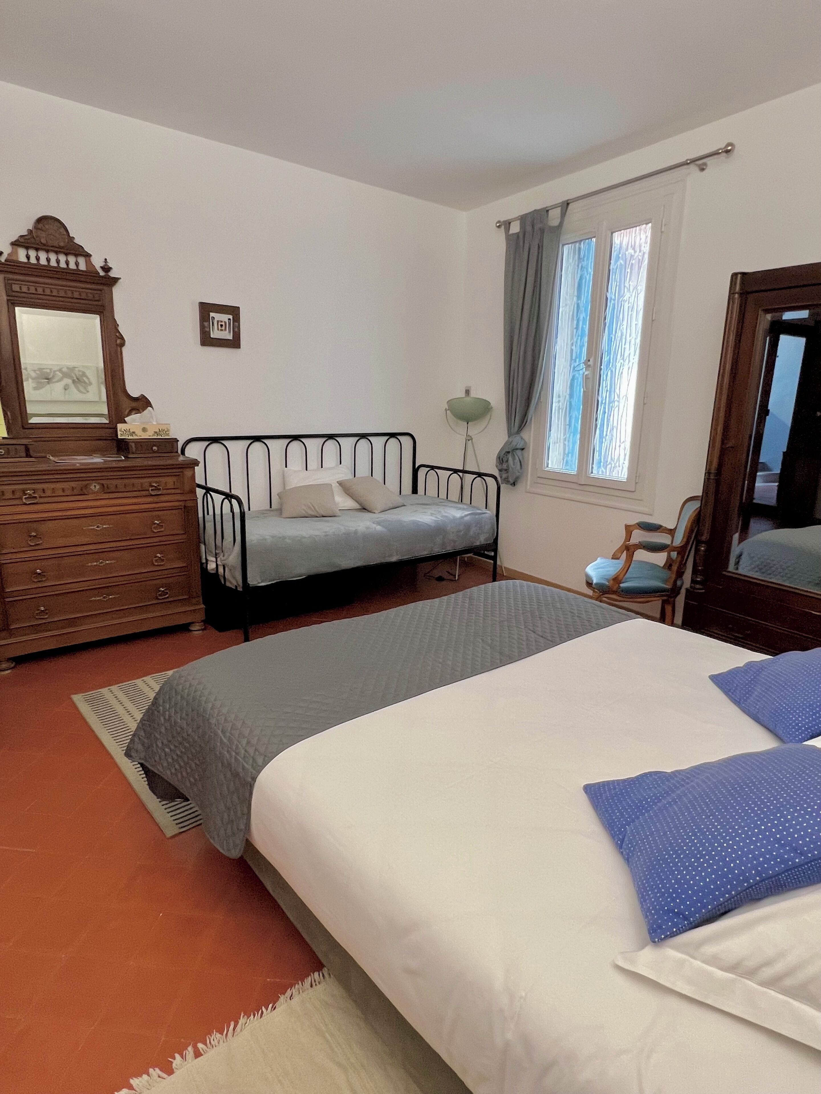 Un dormitorio con dos camas, un aparador, un espejo, una silla y una ventana con cortinas.