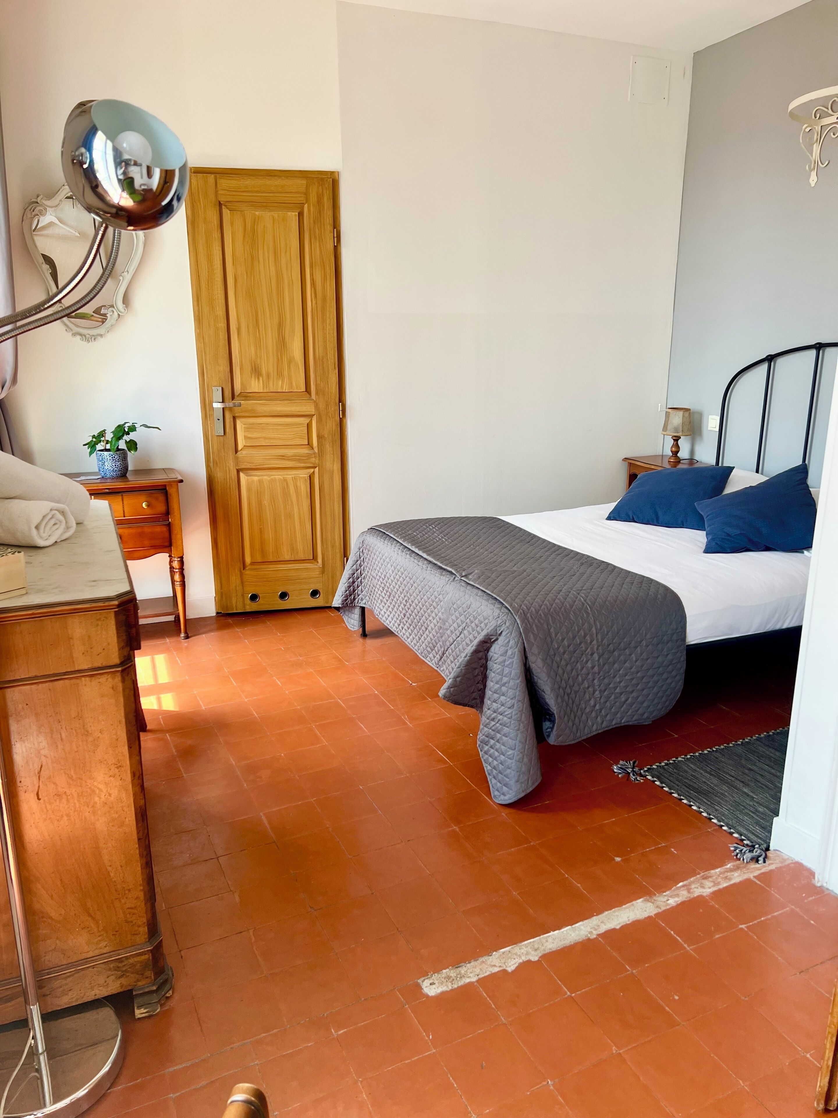 Una camera da letto con un letto, un armadio in legno, un comodino con una lampada e uno specchio appeso al muro.