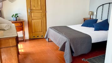 Una camera da letto con un letto, un armadio in legno, un comodino con una lampada e uno specchio appeso al muro.
