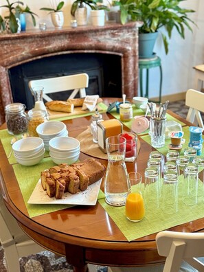 A breakfast table set with various dishes, including bread, butter, and a pitcher of orange juice. - Entre MIDI - Maison d'Hôtes - B&B (Capestang)
