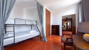 Une pièce avec un lit superposé, une porte en bois, un miroir, une chaise et une table.
