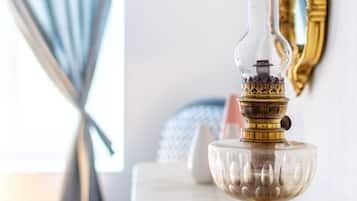 Une lampe à huile en laiton, dotée d’un pied en verre, posée sur une surface en marbre.