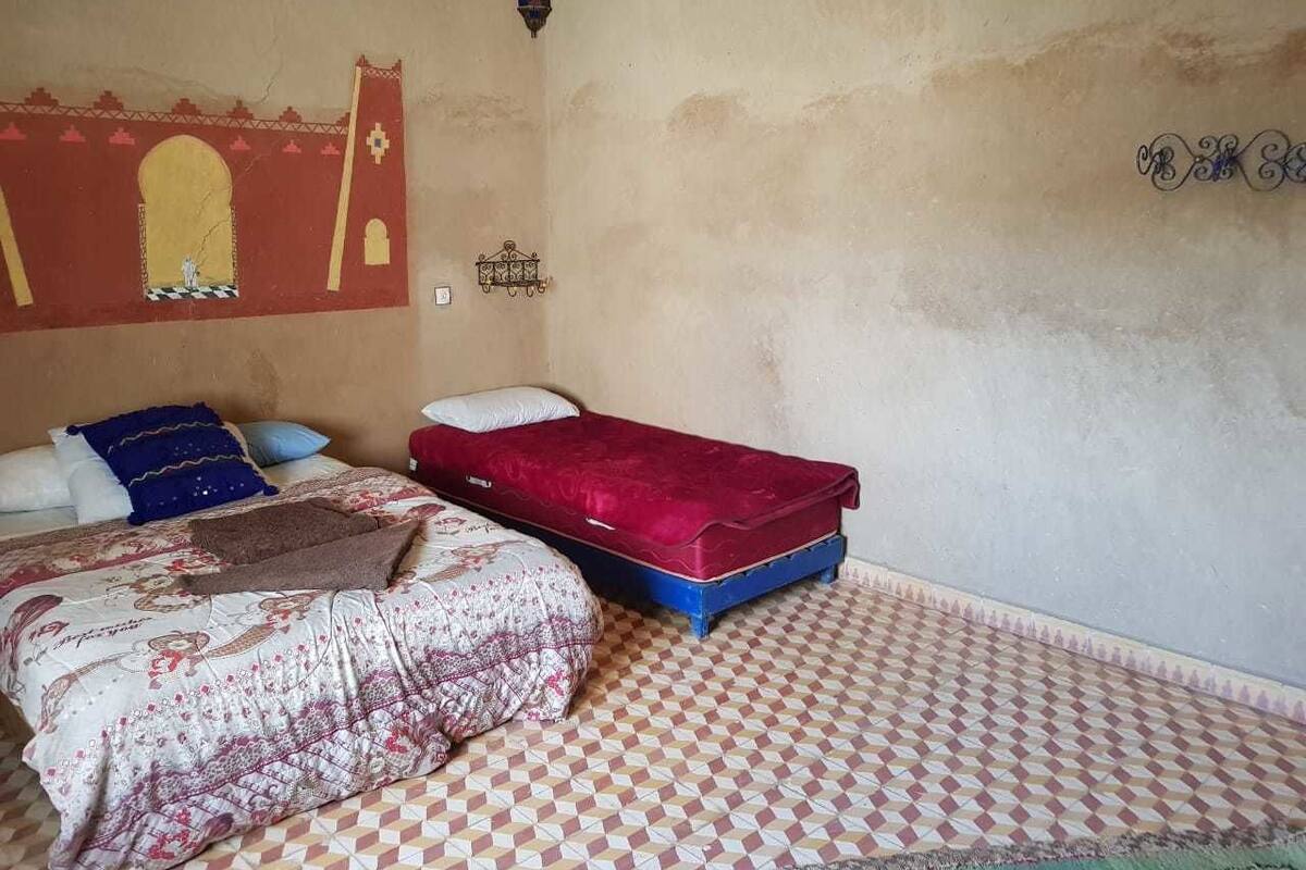 A room with a bed, a mattress on the floor, and a wall with a decorative pattern.