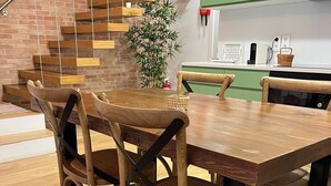 A modern kitchen with green cabinets, a wooden dining table, and a staircase with wooden steps. - Porta 20 - Vacation Home (Loulé)