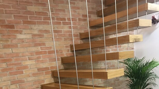 A modern staircase with wooden steps and metal railings against a brick wall. - Porta 20 - Vacation Home (Loulé)