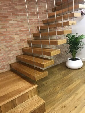 A modern staircase with wooden steps and metal railings against a brick wall. - Porta 20 - Vacation Home (Loulé)