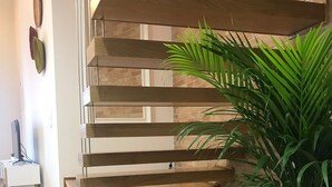 A wooden staircase with a modern design, a potted plant, and a white side table with a lamp. - Porta 20 - Vacation Home (Loulé)