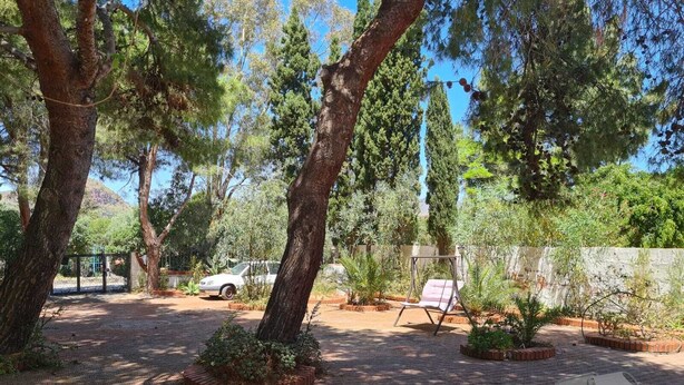 A patio area with a swing chair, a table, and a car parked in the background.