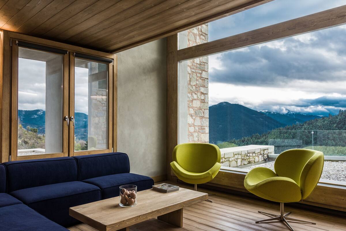 A modern living room with a blue sofa, a wooden coffee table, and a yellow armchair.