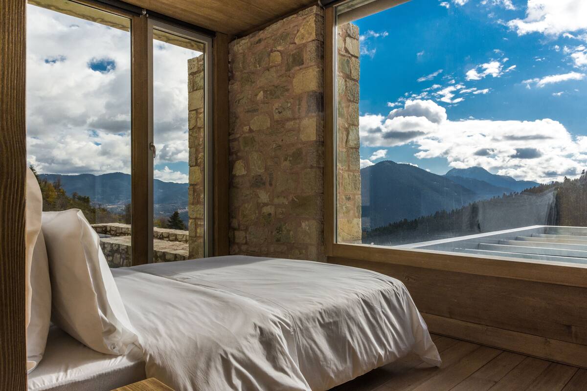 A bedroom with a large window offering a mountain view.