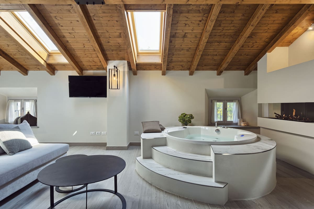A spacious living area with a large skylight, a built-in hot tub, a flat-screen TV, and a fireplace.