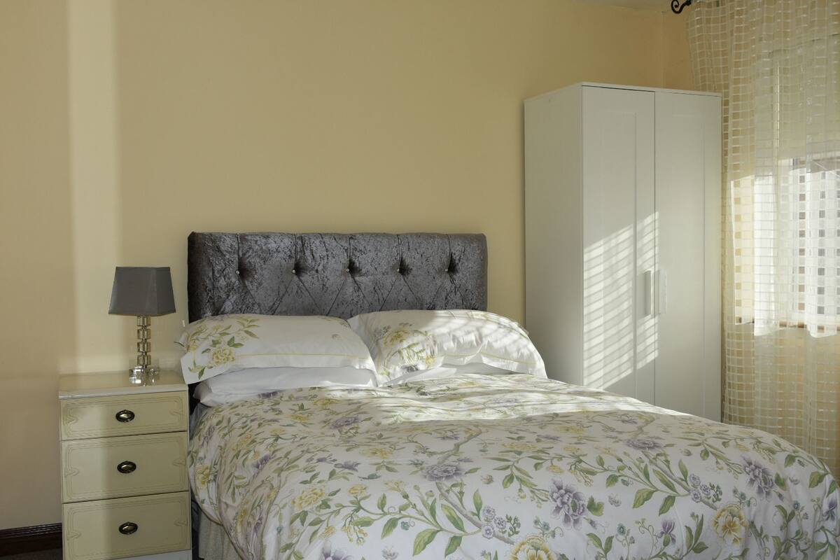 A bedroom with a bed, a nightstand, a lamp, and a wardrobe.