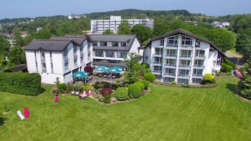 A multi-story hotel with a central courtyard, surrounded by well-maintained lawns and trees.