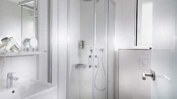 Un baño moderno con cabina de ducha de vidrio, un lavabo blanco y un espejo sobre él.