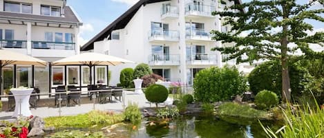 A hotel with a pond, outdoor seating, and a well-maintained garden.