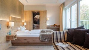 A modern hotel room with a large bed, a sofa, and a window providing a view of the outdoors. - Hotel Derichsweiler Hof (Nümbrecht)