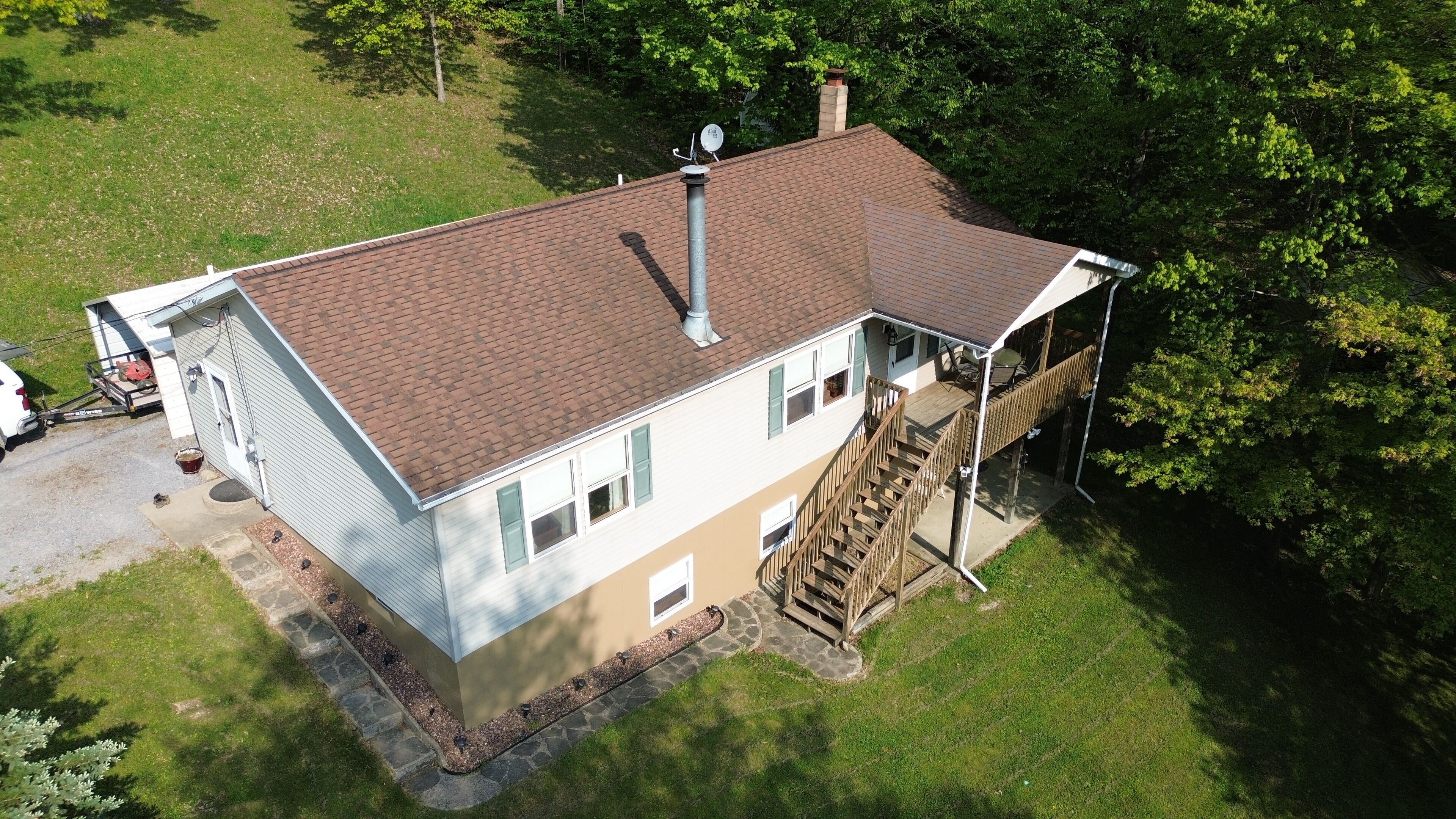 A two-story house with a brick roof, a chimney, a covered porch, and a staircase leading to an upper level.