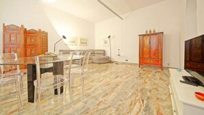 A dining area with a glass table and chairs, a sofa, and a cabinet with ornate doors. - DolceVita Apartments N. 250 (Venice)