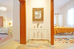 Enter through the elegant archway to a spacious room featuring a large mirror, sink, and decorative bowls.