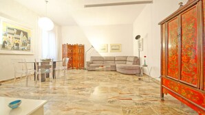 A living room with a marble floor, a sofa, a cabinet, and a dining area with chairs and a table. - DolceVita Apartments N. 250 (Venice)