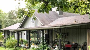 A house with a covered porch, surrounded by lush greenery. - Shepherds Retreat - 2 miles to I-65 (Montevallo)
