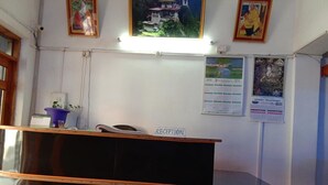 Un comptoir d’accueil avec une pancarte indiquant « RÉCEPTION », dans une pièce dont les murs sont ornés de tableaux encadrés et où se trouve un calendrier.