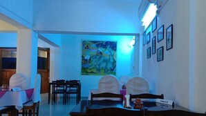 Un espace repas avec des tables et des chaises, un tableau accroché au mur et une plaque nominative posée sur la table.